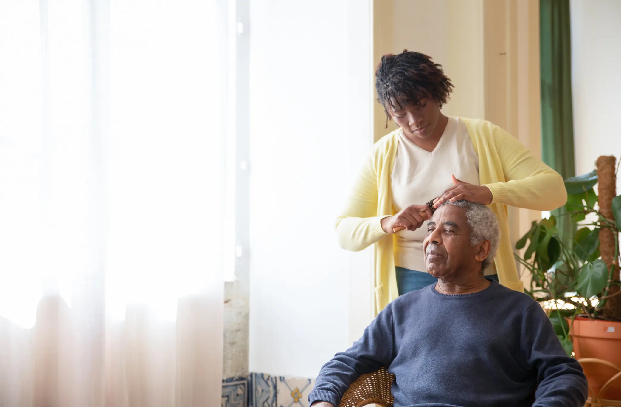 Caregiver gently brushing an older man's hair at home, providing respite care in New Orleans for his family